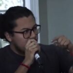 Moisés Avilés, presidente de la asociación estudiantil, cuestiona con un micrófono la presencia de la asambleísta en el acto de la FACSO
